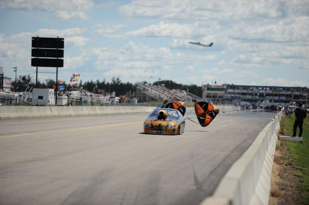 Image de voitures de course d'accélération à Castrol Raceway, de parachute se déployant derrière la voiture et d'un avion décollant en arrière-plan