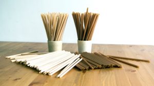 A photo of sugarcane fiber straws in white and brown colours on a wooden table