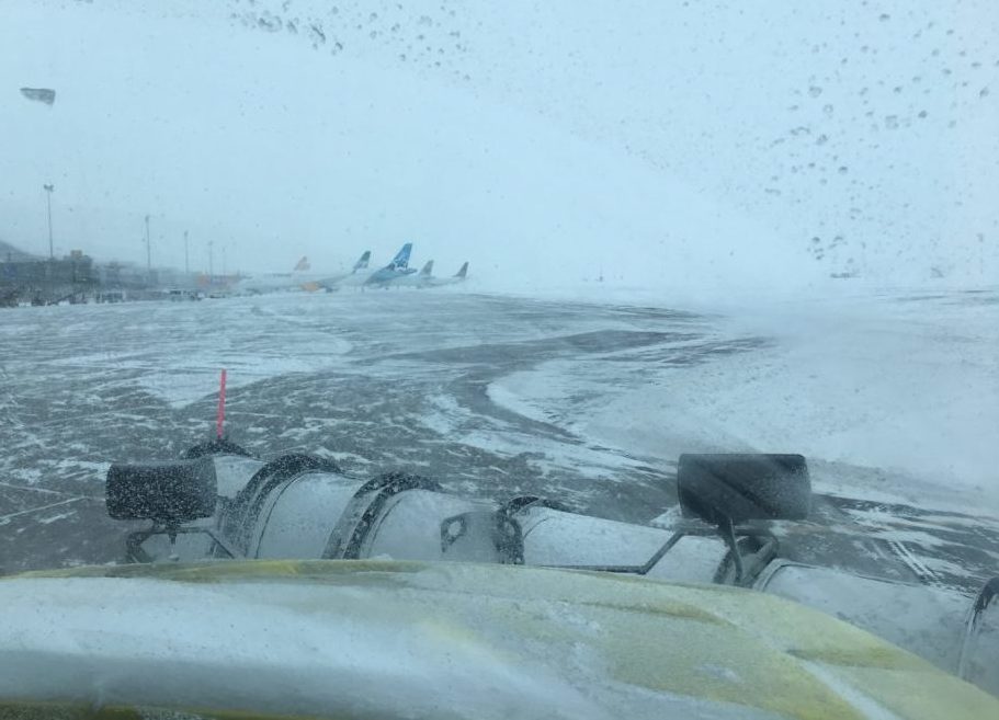 Photo of snow clearing during winter storm with planes in background at Edmonton International Airport.