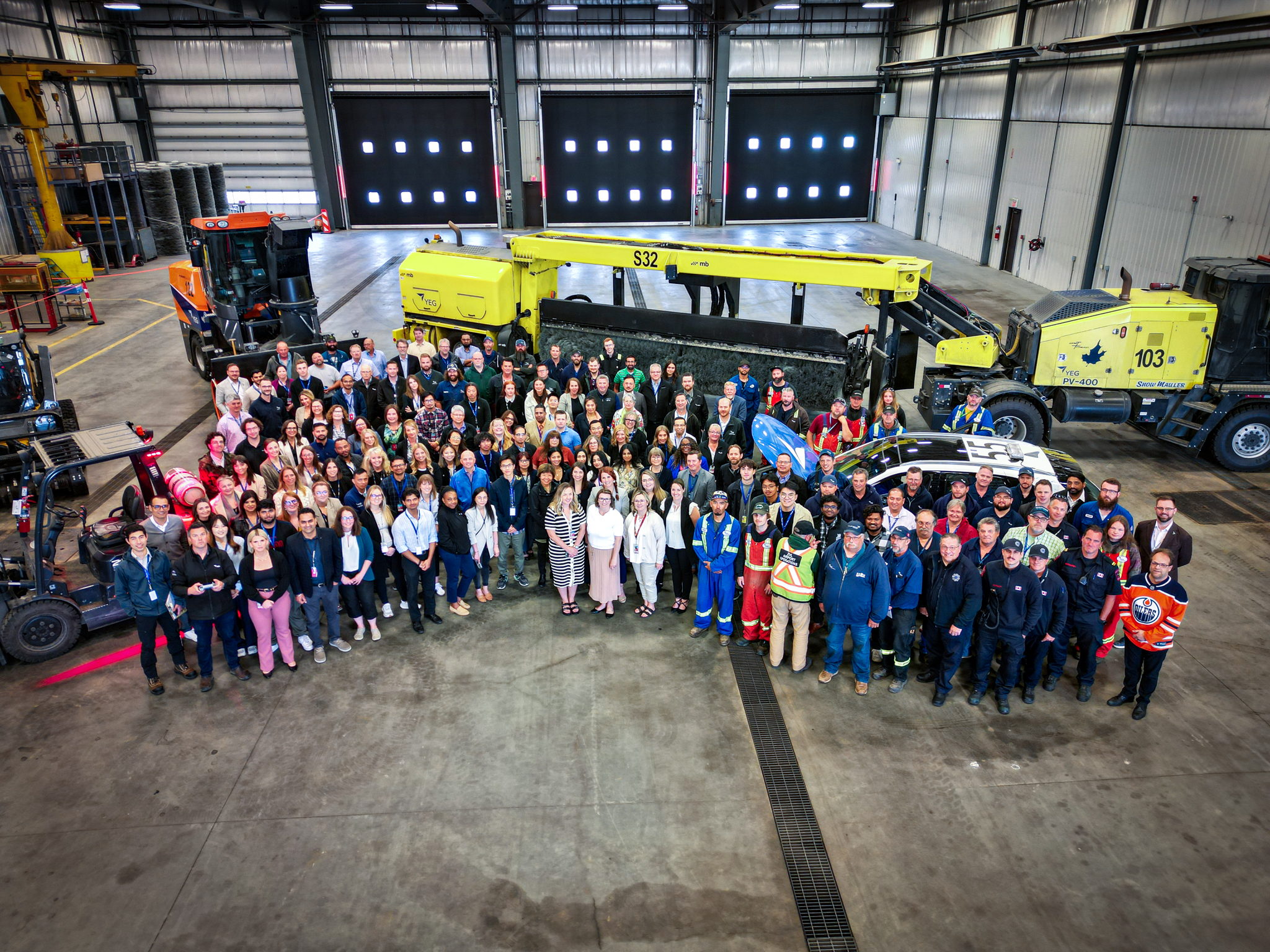 Aerial photo of group of employees standing in front of large equipment