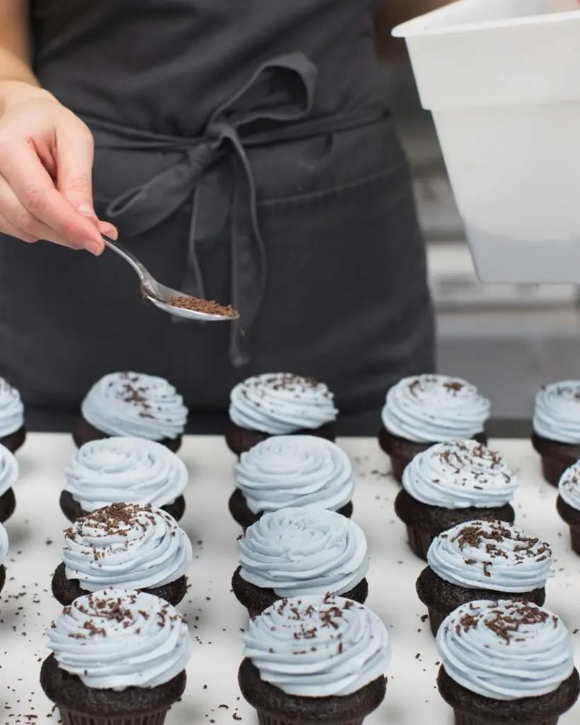 Chef saupoudrant de la garniture sur les  petits gâteaux