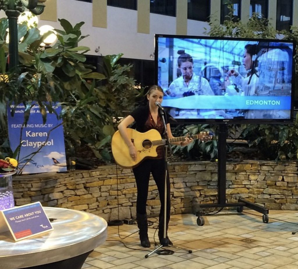La jeune artiste, Karen Claypool, jouant de la guitare et chantant à l'aérogare