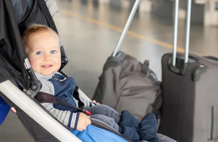 Baby in a stroller surrounded by luggage 