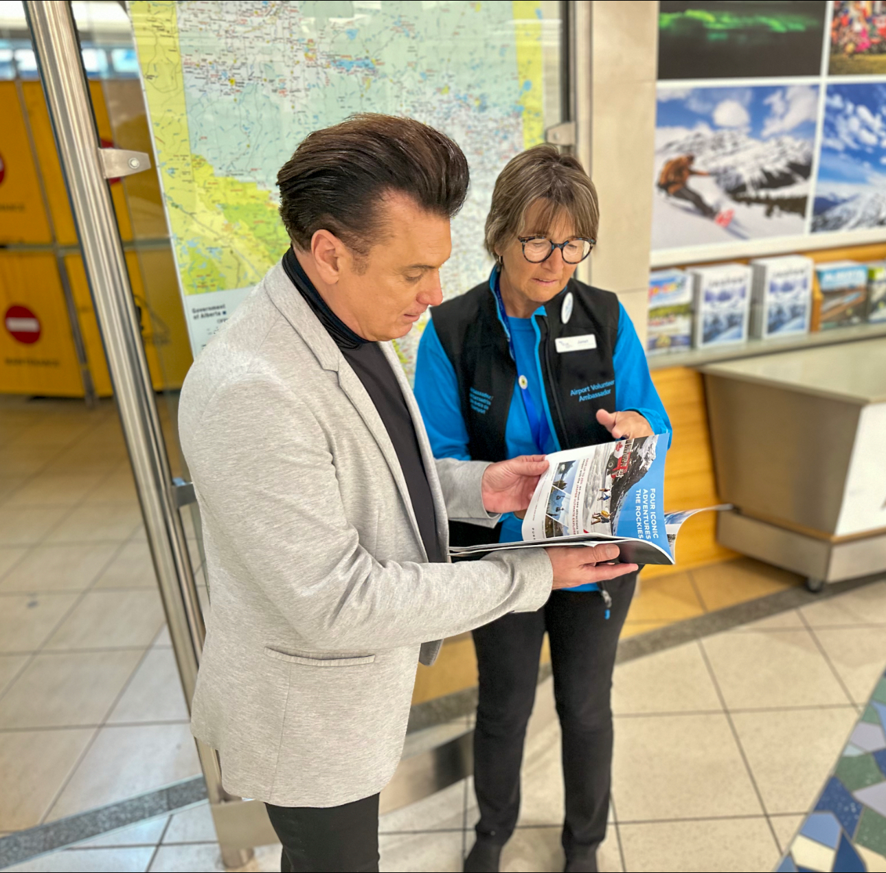 Airport volunteer ambassador showing a passenger a magazine